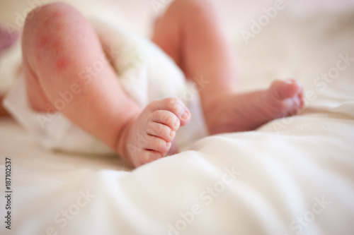 feet of a six months old baby wearing diapers lying in bed at home