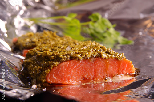 Salmon with pesto and Parmesan sauce, wrapped in foil, ready to bake. Large sea salt and black pepper. Homemade food!