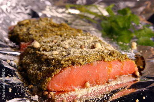 Salmon with pesto and Parmesan sauce, wrapped in foil, ready to bake. Large sea salt and black pepper. Homemade food!