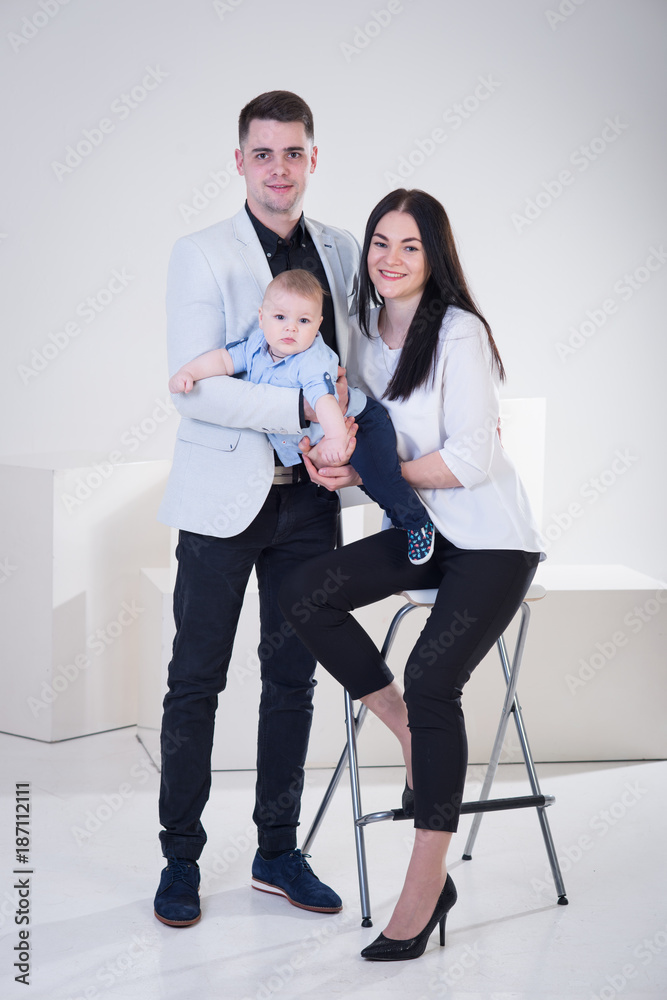Fototapeta premium Young happy family with baby boy shooting in the photo studio, smiling, posing on white background