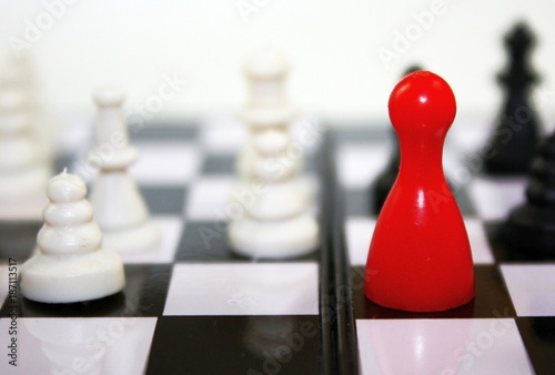 Beautiful black and white contrast with red ludo figure on chessboard. Conceptual leadership game photo.