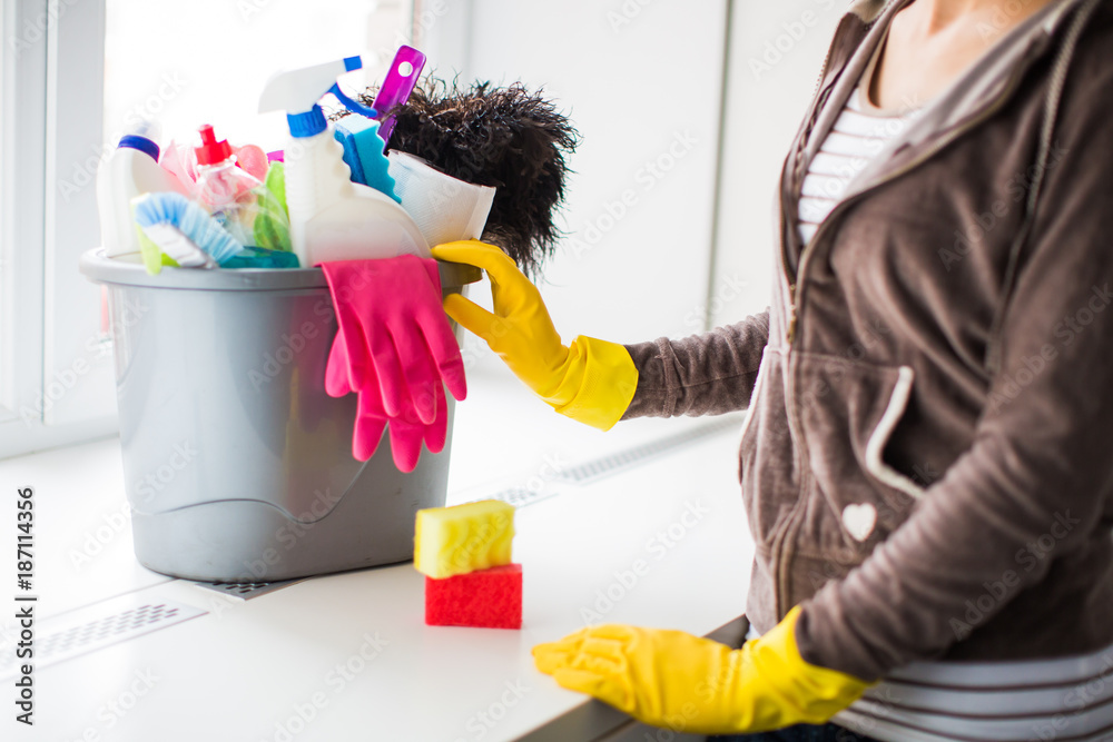A woman standing near things for cleaning in gloves for cleaning at home A woman standing near things for cleaning in gloves for cleaning at home