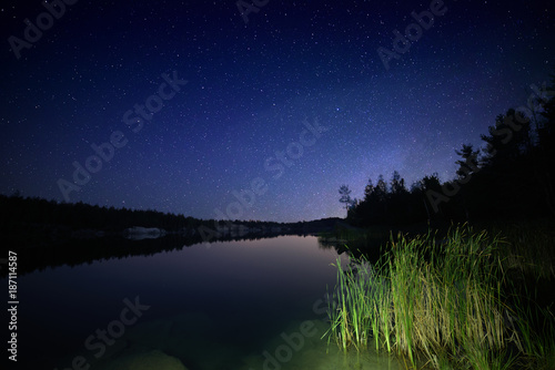 Lake at night with amazing starry sky and reflections in the water. Natural outddors travel dark background. © Roxana