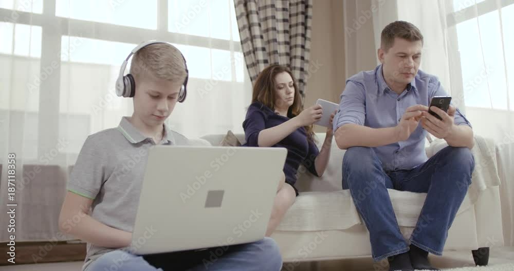 Family of three people uses gadgets and does not communicate. Сoncept of Internet addiction people. Dolly shot 4K Family of three people uses gadgets and does not communicate. Сoncept of Internet addiction people. Dolly shot 4K