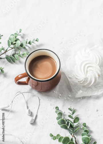Flat lay cocoa cup and meringue on a white background. Morning breakfast inspiration with headphones music