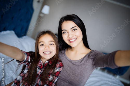Happy mother and daughter taking selfie with smartphone on bed photo