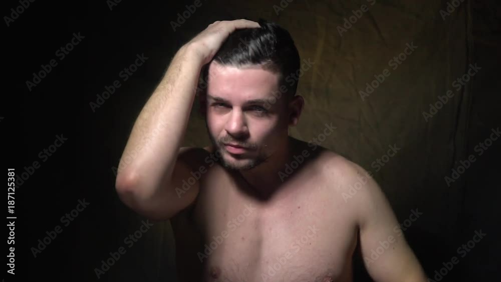 A man stands topless and straightens his hair. A man stands topless and straightens his hair.