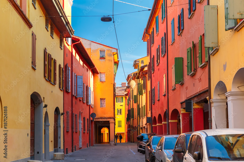 Naklejka premium Medieval street portico with bright colored houses in the Old Town in the sunny day, Bologna, Emilia-Romagna, Italy