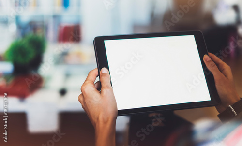 Hipster girl using tablet technology in home atmosphere, girl person holding computer with blank screen on background bokeh, female hands texting on relax holiday, mockup templates