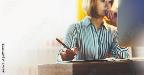 graphic designer working at office with digital stylus on background monitor computer at night, hipster manager using device pen, female hands graw on portable tablet, work process photo