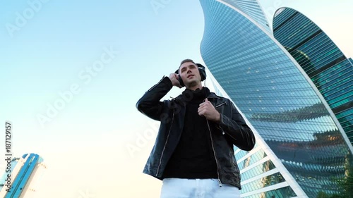 Young handsome man listening to music with pro headphones in the city strreet 4K photo