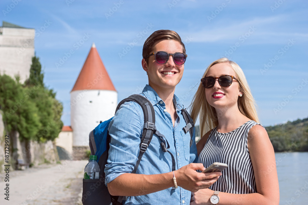 Happy smiling tourists with smartphone in Passau