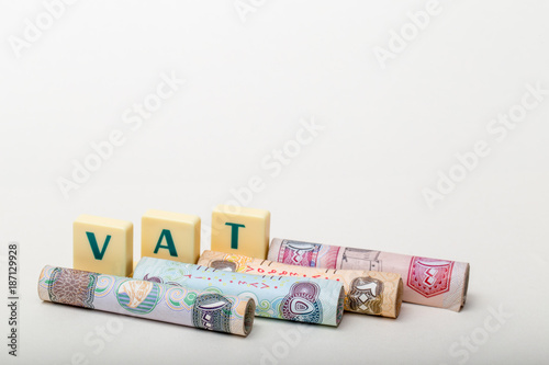 Stacks of  dirham banknotes with the letters VAT  (Value Added Tax) isolated on white background
