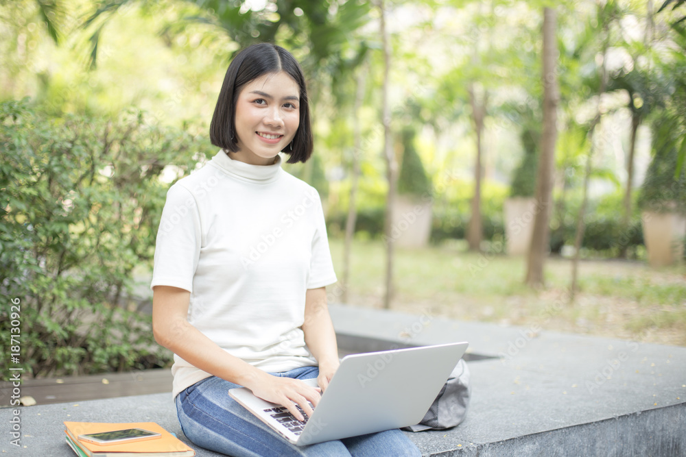 Asian Woman using laptop with attractive smiling at garden. People lifestyle concept. Asian Woman using laptop with attractive smiling at garden. People lifestyle concept.
