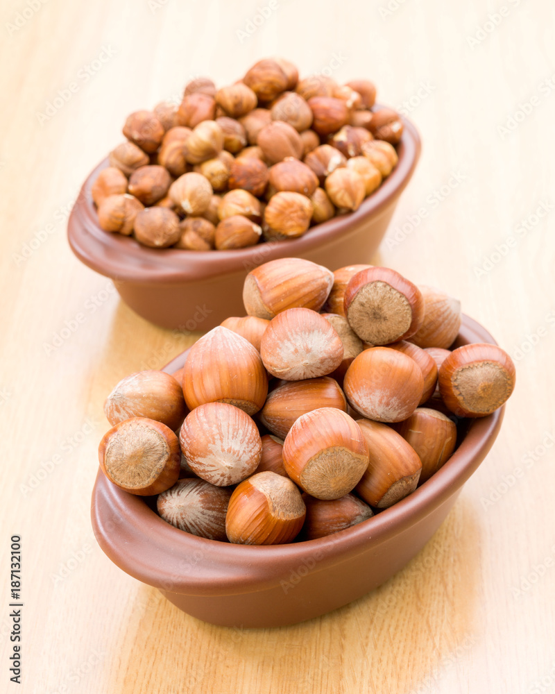 hazelnuts in clay bowl on wooden background hazelnuts in clay bowl on wooden background