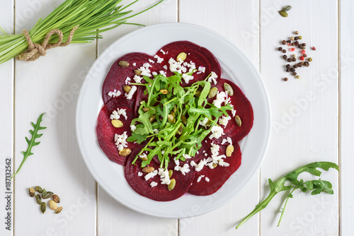 Tableau sur toile Beetroot carpaccio with rucola leaves and pumpkin seeds on wooden white background