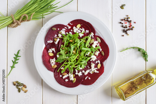 Obraz na płótnie Beetroot carpaccio with rucola leaves and pumpkin seeds on wooden white background