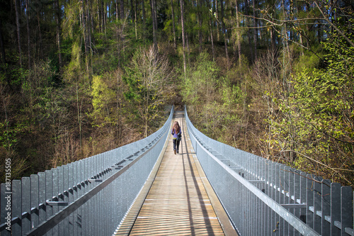lonely young woman crosses a bridge, she is walking in a forest