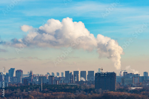 Steaming chimneys on a background of city houses and against the azure sky