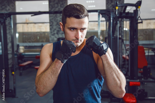Portrait of boxer posing at gym in gloves.