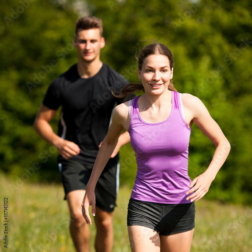 active young youple running cross country in nature on a fores path