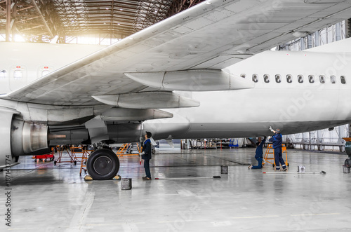 Several people wash the aircraft in the hangar for maintenance, view of the chassis, wing and tail.
