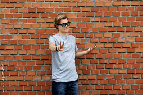 Attractive teenage boy in urban background.Portrait of teenage boy showing victory symbol at the camera.