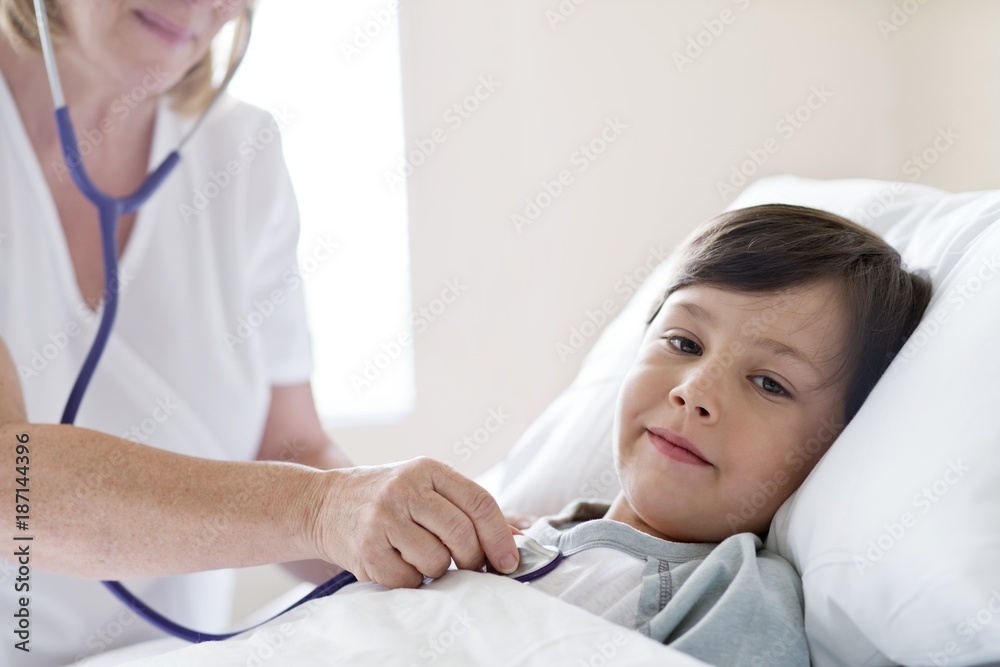 Boy in hospital bed, nurse using stethoscope Boy in hospital bed, nurse using stethoscope