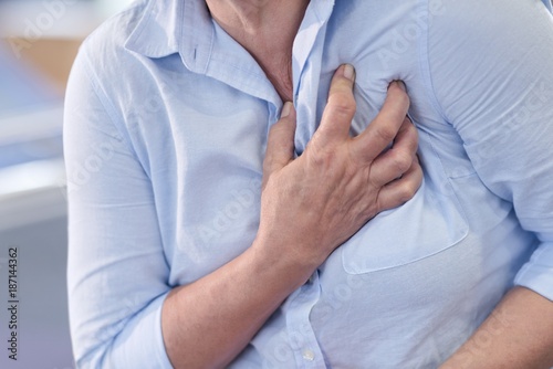 Woman clutching her chest, cropped view