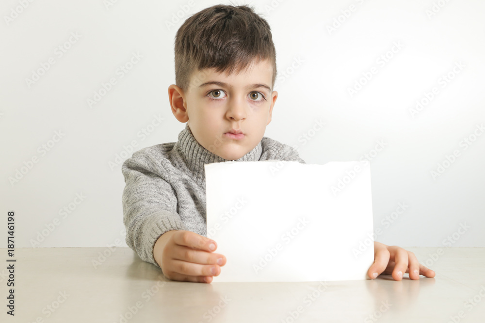 Studio portrait of young boy holding white blank paper Studio portrait of young boy holding white blank paper