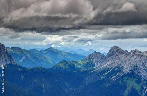Forests  ridges and rocky limestone peaks under dramatic dark storm clouds in Rinaldo mountain group Carnic Alps with Julian Alps in background  Veneto and Friuli Venezia Giulia regions Italy Europe
