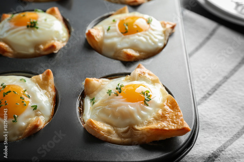 Baking mold with tasty eggs in dough, closeup