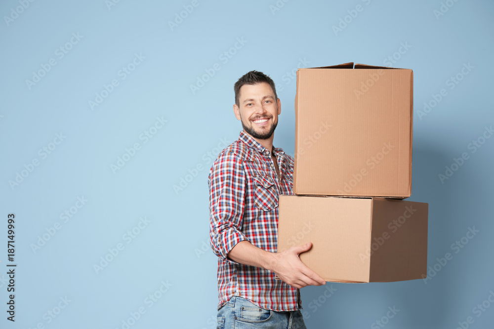 Man with moving boxes near color wall - obrazy, fototapety, plakaty 