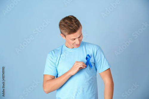 Konstfotografi Young man wearing t-shirt with blue ribbon on color background