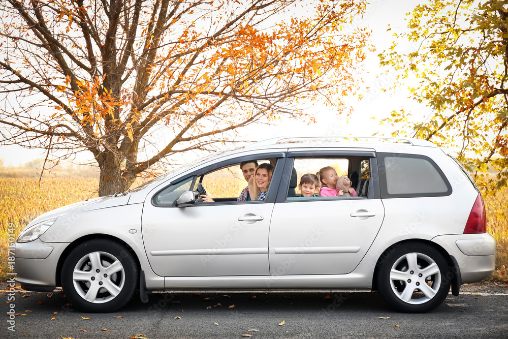 Φωτογραφία Young couple with their little children in car on rural road