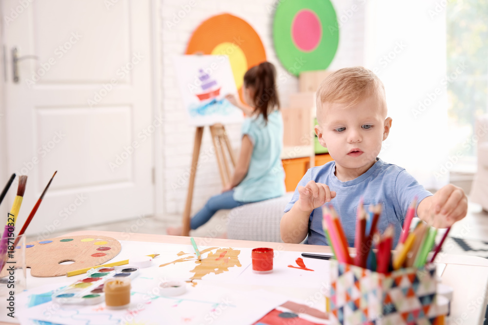 Fototapeta premium Little boy and blurred girl painting indoors