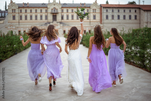 happy bride with the bridesmaids are running playful. View from the back. Wedding concept photo