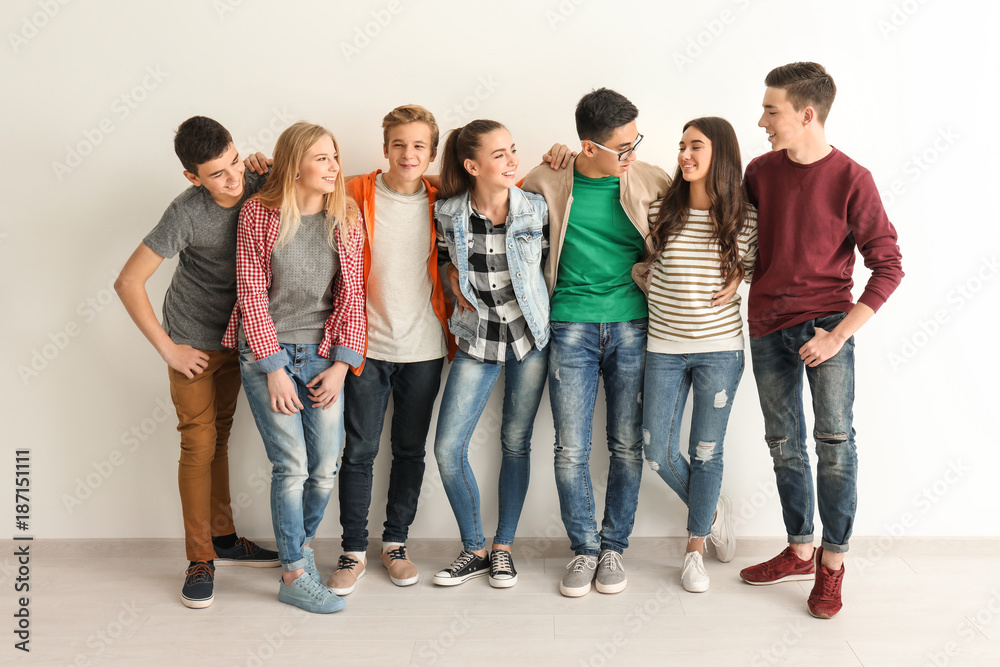 Group of cute teenagers near white wall - obrazy, fototapety, plakaty 