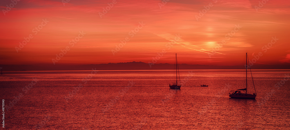 Beautiful colorful sunset at the sea with two sailing boats . Beauty world natural outdoors travel background Beautiful colorful sunset at the sea with two sailing boats . Beauty world natural outdoors travel background