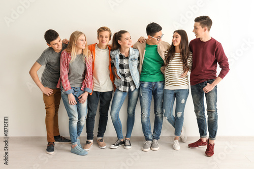 Group of cute teenagers near white wall photo