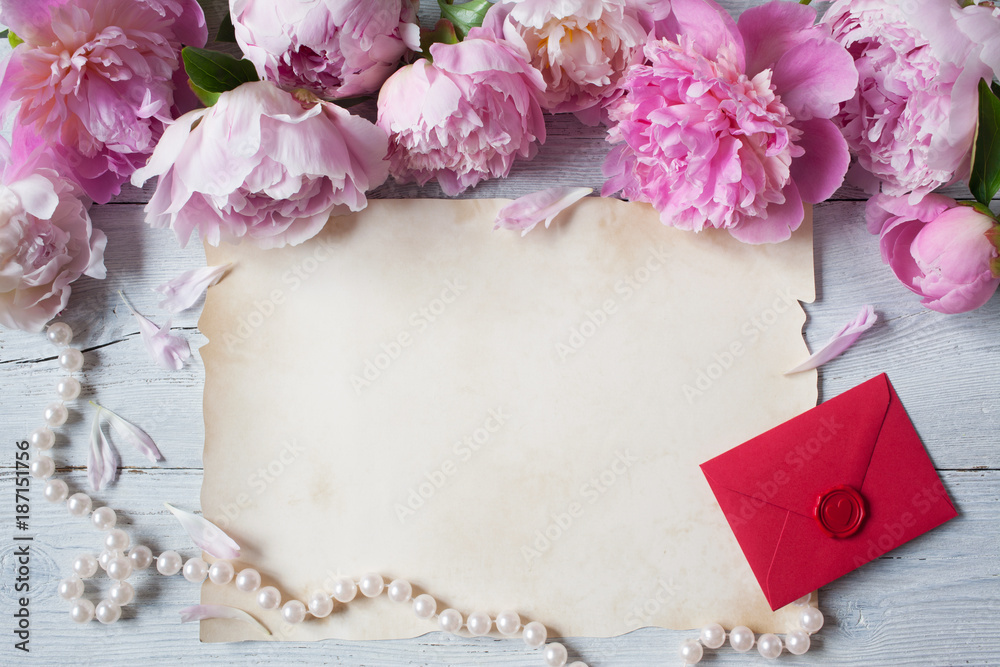 Pink peonies on a wooden background, red envelope and paper Pink peonies on a wooden background, red envelope and paper