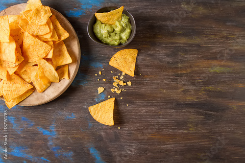 Snack for a party, chips with a tortilla, nachos with sauces: guacamole. Mexican food. Dark background. Top view. Copy space