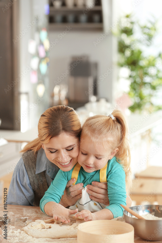 Mother and daughter with dough at table indoors Mother and daughter with dough at table indoors