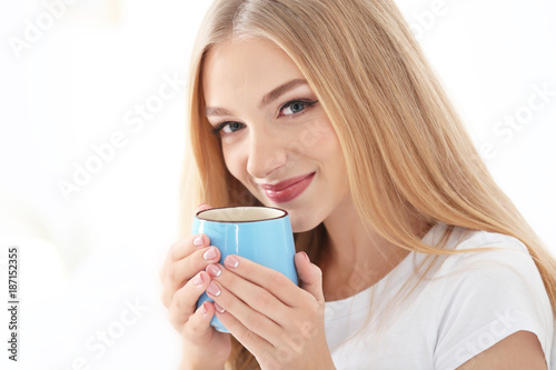 Young beautiful smiling woman with cup of coffee on white background