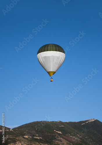 A hot air balloon, in flight to the mountains