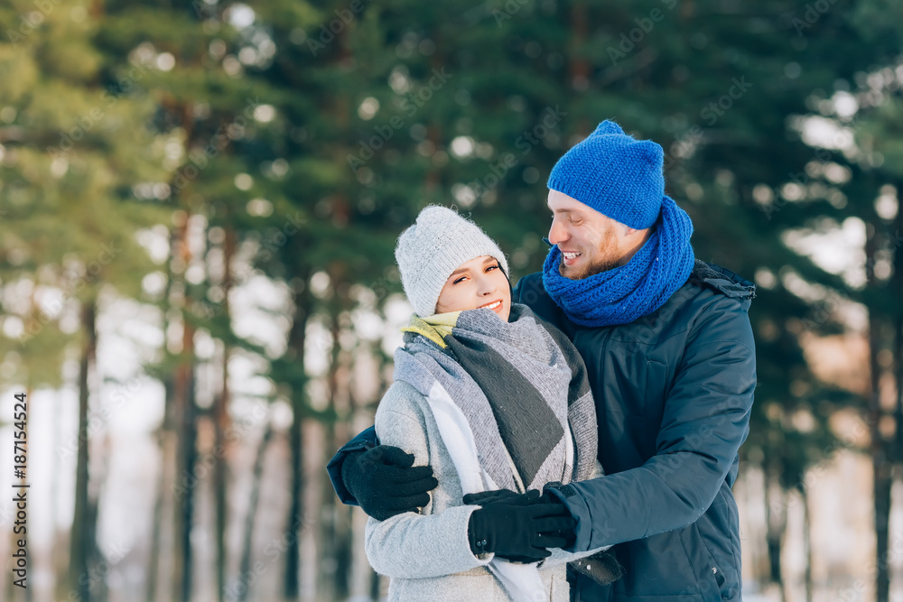 Happy Young Couple in Winter Park laughing and having fun. Family Outdoors.