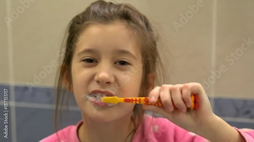 Toddler smiling while brushing her teeth photo
