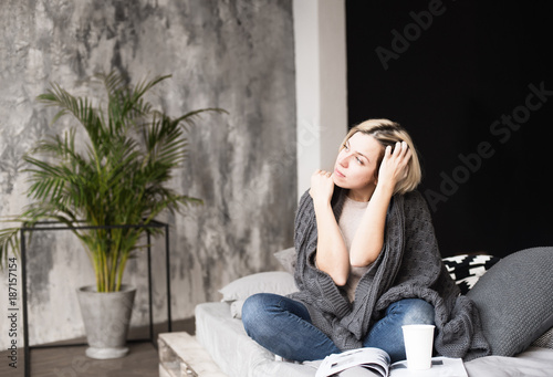 young woman enjoying leisure at home, reading a magazine in bed, cosy home happy and thoughtful emotions