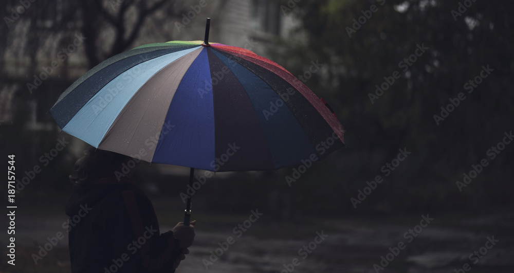Panorama of man with colorful umbrella standing lonely and thinking in the rain weather, blur focus. Concept of loneliness and sadness