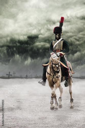 Scary skeleton Napoleon officer riding a white horse with grave crosses behind him in background and with dark and dramatic sky above. The death rider.